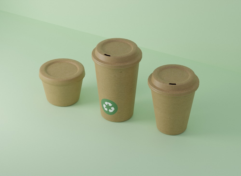 Kraft paper cups with compostable lids on a green background