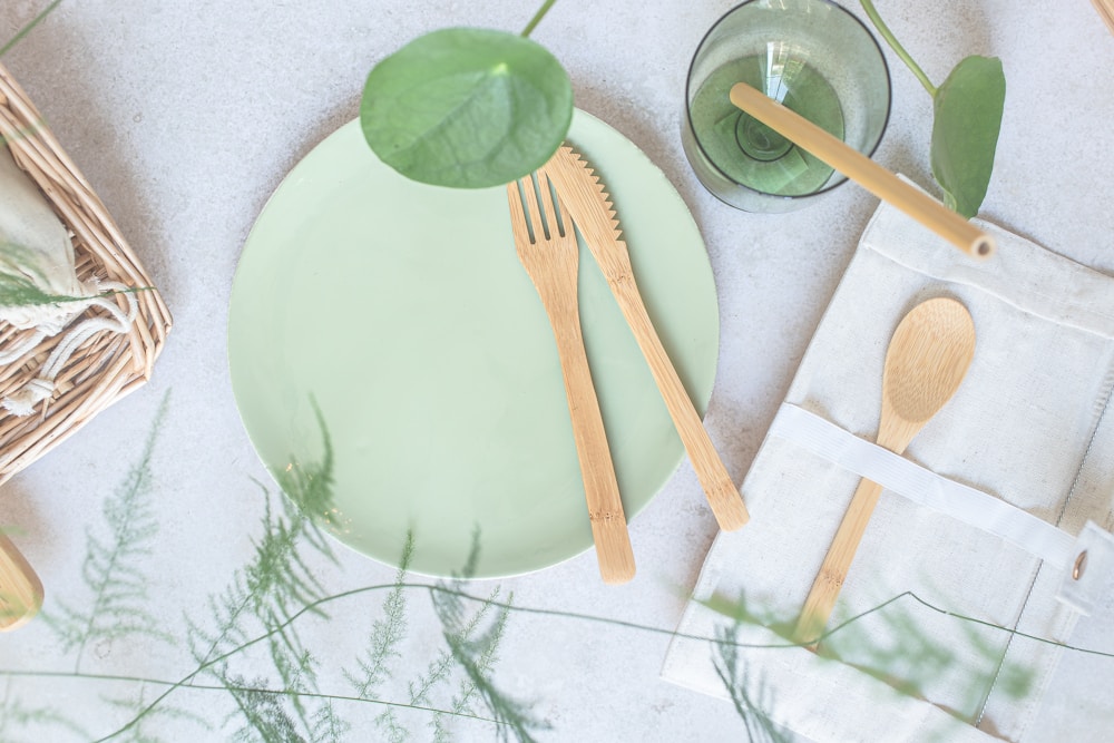 Sage-green plate with bamboo cutlery in a flat-lay setting