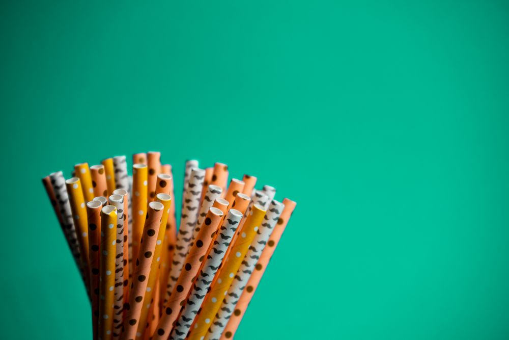 Colourful patterned paper straws against a teal background