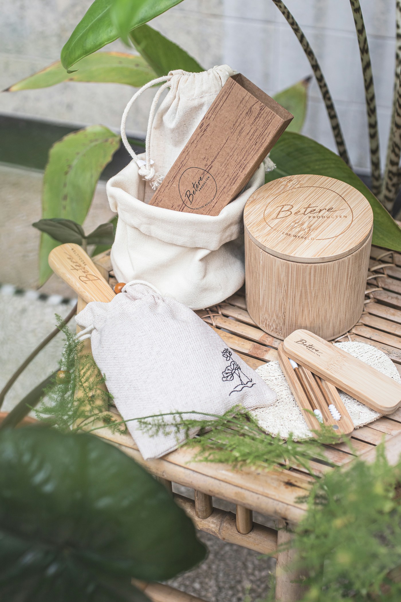 Bamboo and natural-fibre tableware kit arranged among green leaves